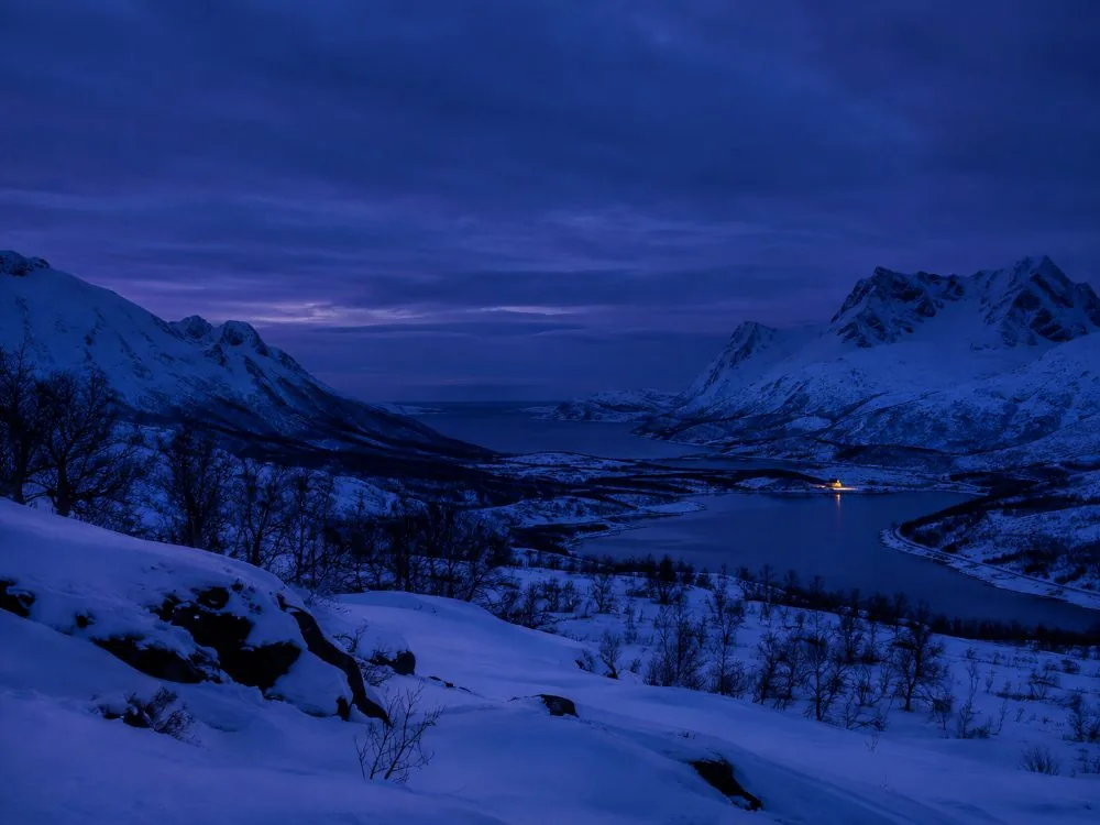 Crépuscule bleu en milieu de journée au-dessus d'une vallée enneigée pendant la nuit polaire